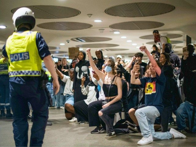 Protesters kneel and raise fists in front of police officers at a subway station during a Black Lives Matter demonstration in Stockholm, Sweden, on June 3, 2020, in solidarity with protests raging across the United States over the death of George Floyd. - Former Minneapolis police officer Derek Chauvin, who …