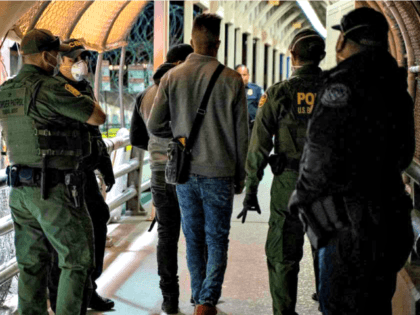 U.S. Border Patrol and Customs and Border Protection agents escort asylum applicants acros