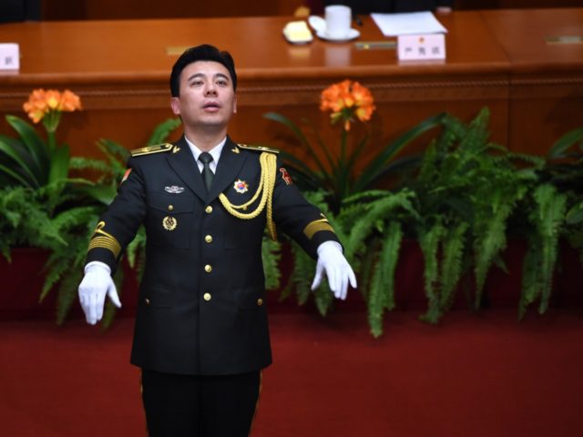 A Chinese People's Liberation Army (PLA) officer conducts delegates as they sing the natio