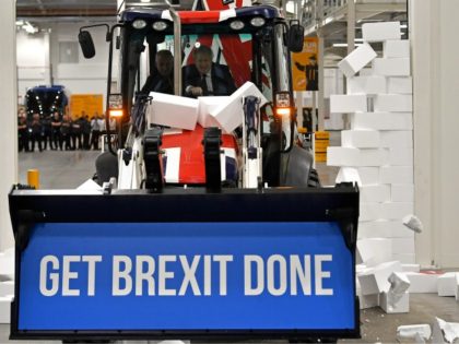 UTTOXETER, ENGLAND - DECEMBER 10: Britain's Prime Minister and Conservative party leader Boris Johnson drives a Union flag-themed JCB, with the words "Get Brexit Done" inside the digger bucket, through a fake wall emblazoned with the word "GRIDLOCK", during a general election campaign event at JCB construction company on December …