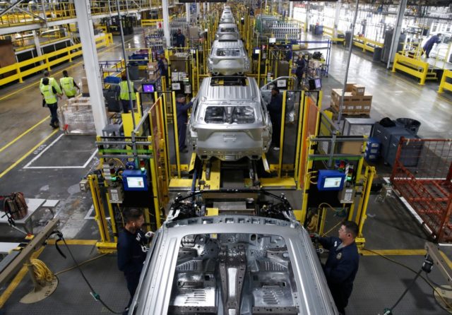 Workers assemble cars at the newly renovated Ford's Assembly Plant in Chicago, June 2