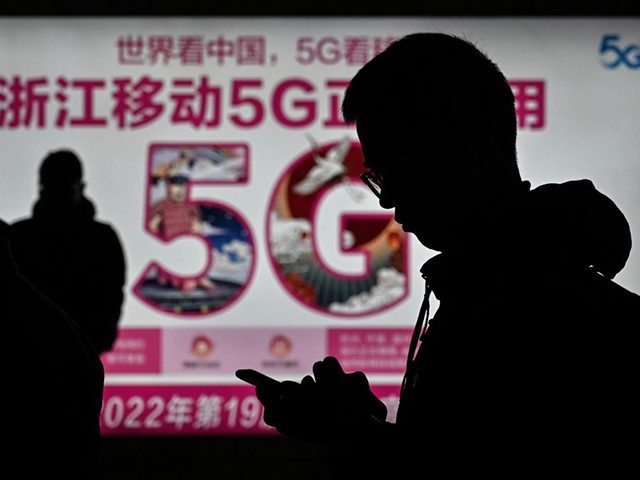 A man looks at his smartphone near an advertisement for 5G internet at the railway station in Hangzhou, Zhejiang province on December 3, 2019. (Photo by HECTOR RETAMAL / AFP) (Photo by HECTOR RETAMAL/AFP via Getty Images)