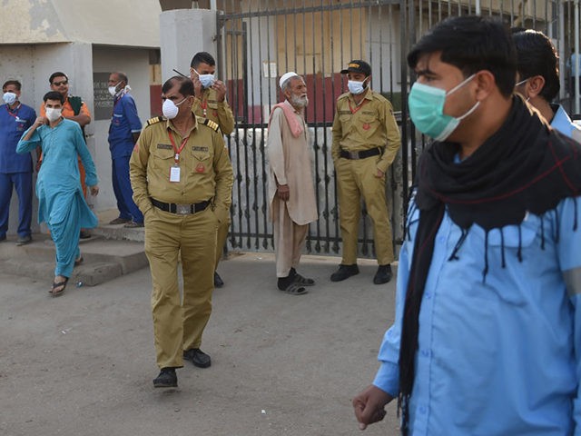 Security personnel (C) and hospital staff wearing facemasks stand outside an hospital entr