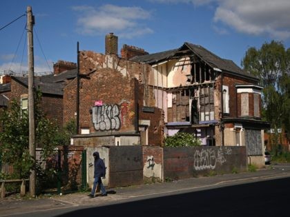 A man walks past a derelict house in Moss Side in Manchester, north-west England on May 11