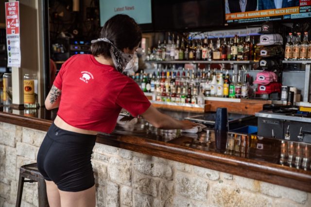 A bartender cleans the counter at a bar in Austin, Texas on Friday, May 22, 2020. - Austin