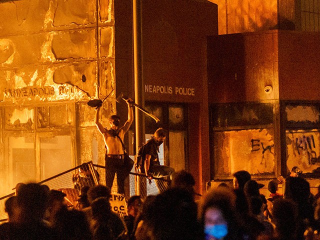 TOPSHOT - Flames from a nearby fire illuminate protesters standing on a barricade in front of the Third Police Precinct on May 28, 2020 in Minneapolis, Minnesota, during a protest over the death of George Floyd, an unarmed black man, who died after a police officer kneeled on his neck …