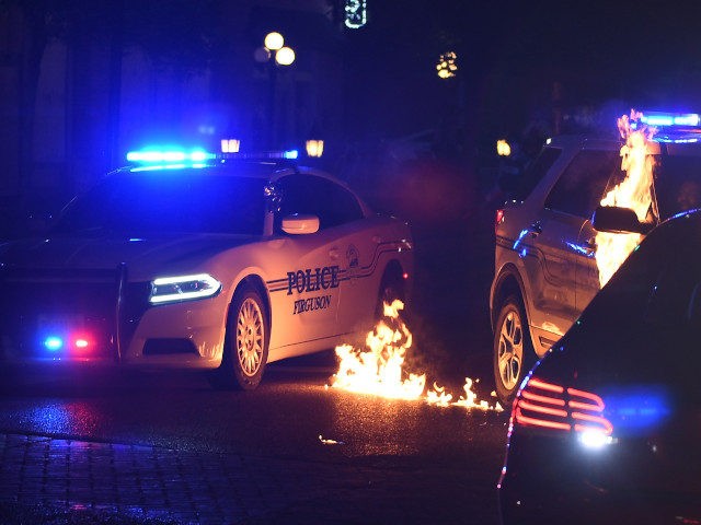 FERGUSON, MO - MAY 31: A Ferguson police officer reacts as a flammable object is thrown a a police cruiser following a protest at the Ferguson Police Department on May 31, 2020 in Ferguson, Missouri. Major cities nationwide saw demonstrations over the death of George Floyd, some of which turned …