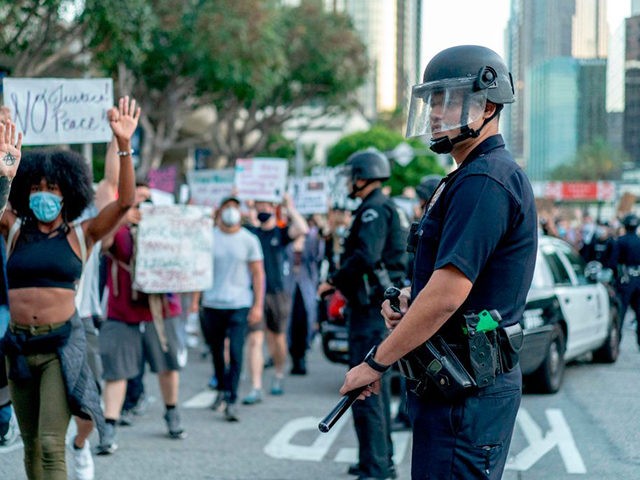 Protesters march past LAPD officers during a demonstration over the death of George Floyd while in Minneapolis Police custody, in downtown Los Angeles, California, June 6, 2020. - Demonstrations are being held across the US following the death of George Floyd on May 25, 2020, while being arrested in Minneapolis, …