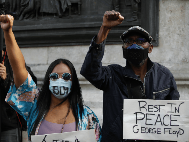 People wearing face masks raises their fist to protest in place de la Republique in Paris,