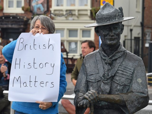 A woman holds a placards reading "British History Matters" alongside a statue of Robert Baden-Powell, the founder of the Scout movement, on the quayside in Bournemouth, southern England, on June 11, 2020, after the council said it would remove the statue. - Authorities in the seaside town of Bournemouth were …
