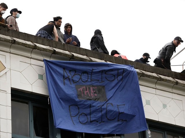 A banner which reads "abolish the police" hangs from a building in an area being called the Capitol Hill Autonomous Zone (CHAZ) located on streets reopened to pedestrians after the Seattle Police Department's East Precinct was vacated in Seattle, Washington on June 12, 2020. - Seattle's mayor told Donald Trump to "Go back to your bunker" June 11, escalating a spat after the president threatened to intervene over a police-free autonomous zone protesters have set up in the western US city. (Photo by Jason Redmond / AFP) (Photo by JASON REDMOND/AFP via Getty Images)