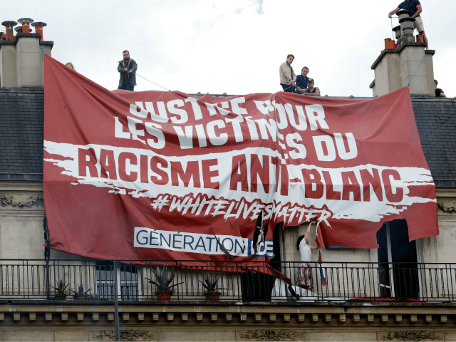 Residents try to remove a banner installed on the roof by members of far right group Generation Identitaire (GI) and reading 'victims of anti-white racism' during a 'Black Lives Matter' protest against racism and police brutality, on Place de la Republique in Paris on June 13, 2020. (Photo by Thomas …