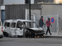 People walk past a burnt van in the Gresilles area of Dijon, eastern France, on June 15, 2020, as new tensions flared in the city after it was rocked by a weekend of unrest blamed on Chechens seeking vengeance for an assault on a teenager. - Police sources said the …