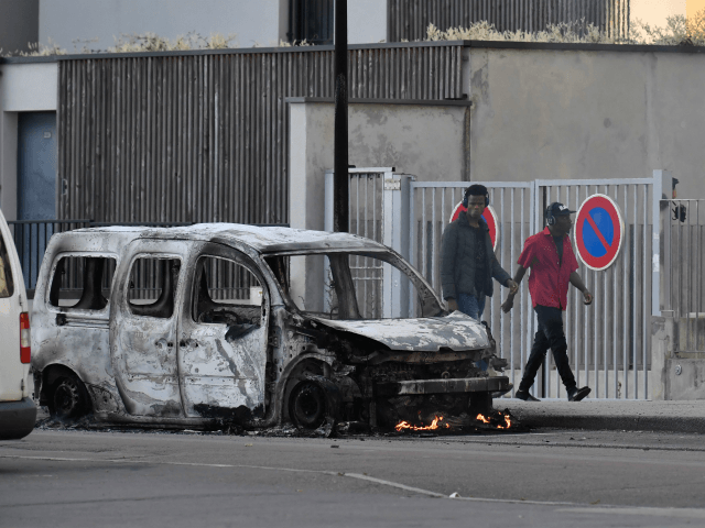 People walk past a burnt van in the Gresilles area of Dijon, eastern France, on June 15, 2