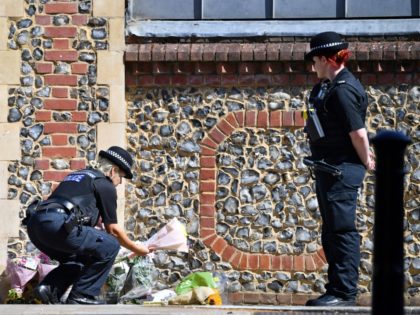 TOPSHOT - A police officers lays flowers, given by a member of the public, at an entrance of Forbury Gardens park in Reading, west of London, on June 22, 2020, the scene of the June 20 stabbing spree. - A suspect held on suspicion of stabbing three people to death …