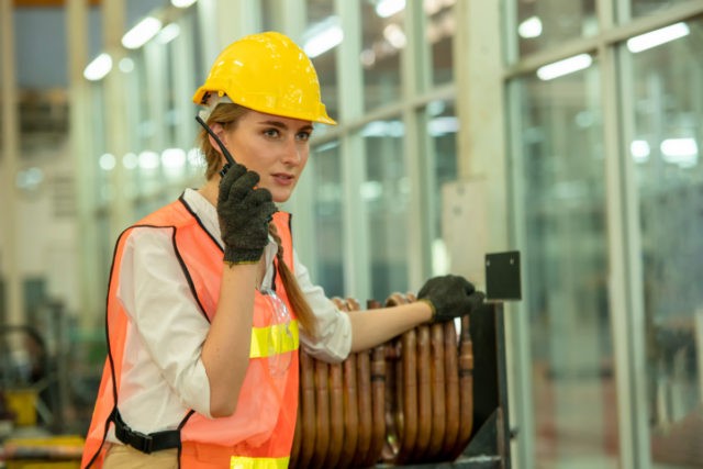 Engineer woman using radio communication at factory.