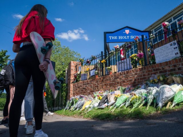 WOKINGHAM, ENGLAND - JUNE 22: A girl holds her skateboard as students lay flowers and pay their respects to the murdered school teacher James Furlong outside The Holt School, on June 22, 2020 in Wokingham, England. Khairi Saadallah, a 25-year-old refugee from Libya, was arrested on Saturday evening suspected of …