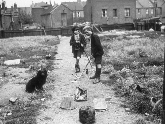 Two London slum boys playing golf on a home made course, consisting of old buckets. (Pho