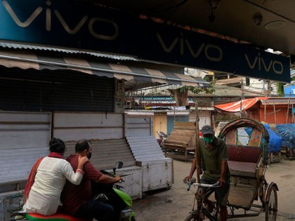 Commuters pass by an advertising board of Chinese mobile phone maker VIVO on a street in a closed market in Siliguri on June 22, 2020. - Chinese sponsorship of India's biggest sporting event was under threat on June 19 after a border clash between the two countries sparked calls in …