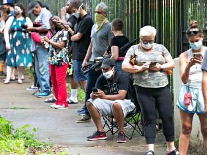 Steven Posey checks his phone as he waits in line to vote, Tuesday, June 9, 2020, at Central Park in Atlanta. Voters reported wait times of three hours. (AP Photo/John Bazemore)