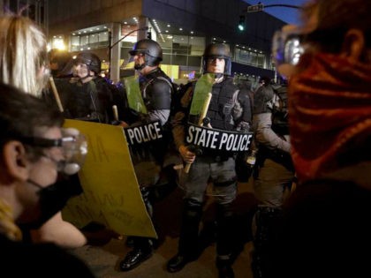 Protesters stand in front of Kentucky State Police officers as they protest the deaths of