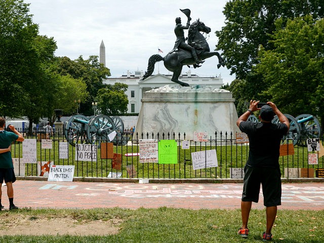 People visit Lafayette Park where protest signs are seen along the fencing that surrounds a statue of President Andrew Jackson, Tuesday, June 16, 2020, near the White House in Washington, where protests have occurred over the death of George Floyd, a black man who was in police custody in Minneapolis. …