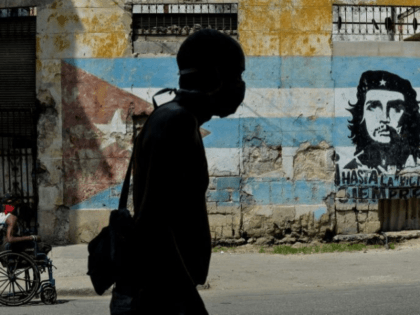 A Cuban man wears a face mask in front of a mural showing revolutionary Che Guevara in Hav