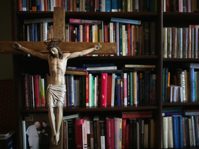 BIRMINGHAM, ENGLAND - AUGUST 11:A crucifx leans against religious academic books at Oscott College on May 8, 2014 in Birmingham, England. St. Mary's College, Oscott opened in 1794 and was designed by the gothic architect Augustus Welby Pugin. The formation for catholic priesthood takes six years living in the college …