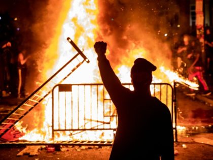 TOPSHOT - A protester raises a fist near a fire during a demonstration outside the White H