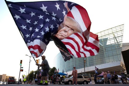 TULSA, OKLAHOMA - JUNE 18: Trump supporter Randall Thom waves a giant Trump flag to passing cars outside the BOK Center June 18, 2020 in Tulsa, Oklahoma. Trump is scheduled to hold his first political rally since the start of the coronavirus pandemic at the BOK Center on Saturday while …