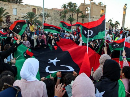 People celebrate with Libyan national flags, some clad in masks due to the COVID-19 corona