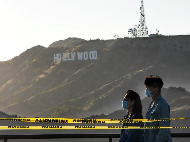 People wearing facemasks walk at the Griffith Observatory with a view of the Hollywood sign at the start of Memorial Day holiday weekend amid the novel coronavirus pandemic in Los Angeles on May 22, 2020. (Photo by Apu GOMES / AFP) (Photo by APU GOMES/AFP via Getty Images)