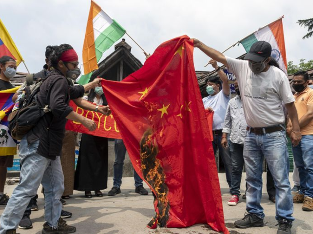 Exile Tibetans and local Indians burn a Chinese national flag during a protest in Dharmsal