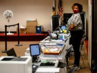 A poll worker wearing a protective mask is seen at the Dunwoody Library on Monday, May 18, 2020, in Dunwoody, Georgia. Georgians were greeted with a few new procedures as they participated in the first day of in-person early voting for the state's June 9 primaries with the coronavirus pandemic …