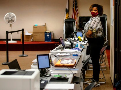 A poll worker wearing a protective mask is seen at the Dunwoody Library on Monday, May 18, 2020, in Dunwoody, Georgia. Georgians were greeted with a few new procedures as they participated in the first day of in-person early voting for the state's June 9 primaries with the coronavirus pandemic …