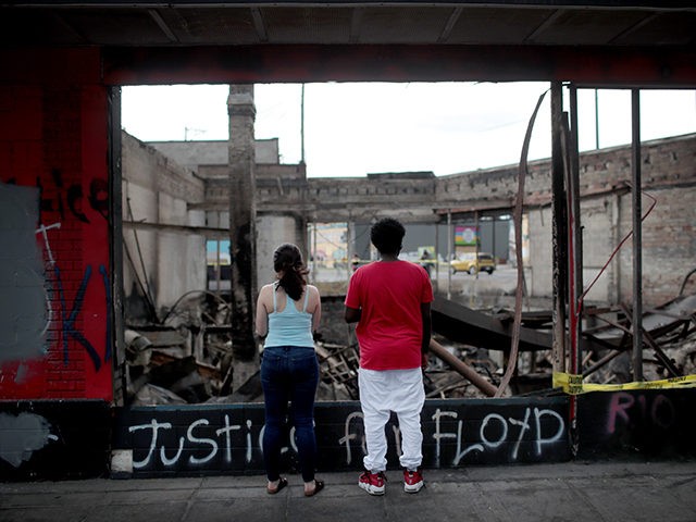 MINNEAPOLIS, MINNESOTA - JUNE 02: People look at the charred wreckage of a building destroyed during last week's rioting which was sparked by the death of George Floyd on June 2, 2020 in Minneapolis, Minnesota. Floyd died on May 25 while in Minneapolis police custody. Officer Derek Chauvin has been …