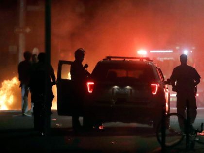 A police car burns, left rear, after being set on fire in Boston, Sunday, May 31, 2020, fo