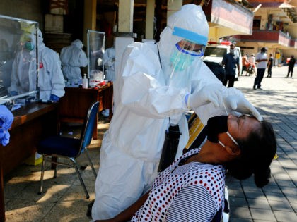 A heath worker takes a nasal swab sample during a public testing for the new coronavirus conducted at a market in Bali, Indonesia on Friday, June 12, 2020. (AP Photo/Firdia Lisnawati)