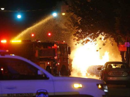 A car explodes as firefighters attempt to douse the flames as protesters march through downtown during a third night of unrest Sunday, May 31, 2020, in Richmond, Va. Gov. Ralph Northam issued a curfew for this evening. (AP Photo/Steve Helber)