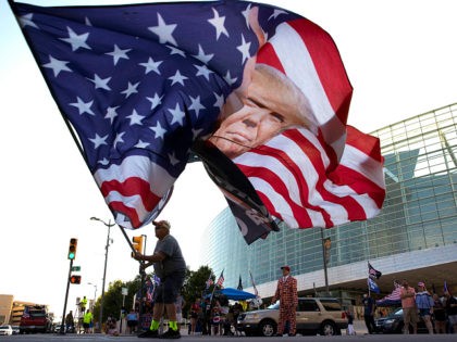 TULSA, OKLAHOMA - JUNE 18: Trump supporter Randall Thom waves a giant Trump flag to passin