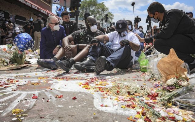 in this June 1, 2020 file photo, an emotional Terrence Floyd, second from right, is comforted as he sits at the spot at the intersection of 38th Street and Chicago Avenue, Minneapolis, Minn., where his brother George Floyd, encountered police and died while in their custody. A dispatcher who was …