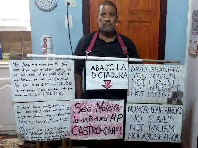 Daniel Llorente, Cuban dissident forced into exile in Guyana, holds protest signs June 22,