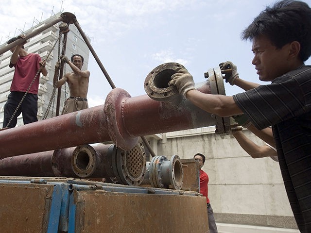 Chinese workers loading steel pipes onto a truck in Beijing, China, Tuesday, Aug 1, 2006.