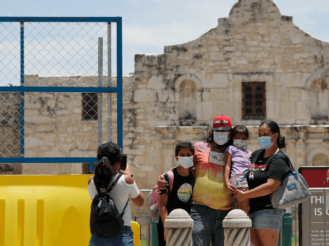 Visitors wearing masks to protect against the spread of COVID-19 pose for photos at the Alamo, which remains closed, in San Antonio, Wednesday, June 24, 2020. Cases of COVID-19 have spiked in Texas and the governor of Texas is encouraging people to wear masks in public and stay home if …