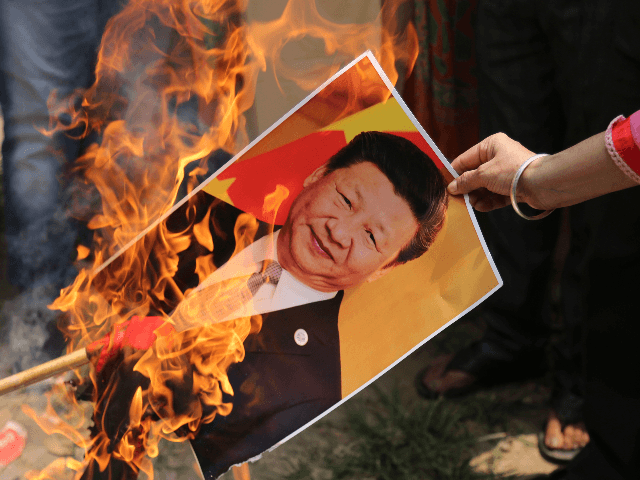 A Bharatiya Janata Party activist burns a photograph of Chinese President Xi Jinping durin