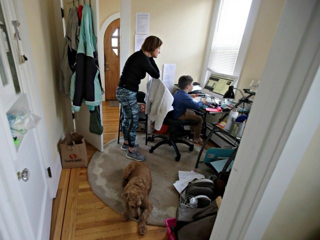 In this Thursday, March 19, 2020, photo, Rebecca Biernat watches as her son Seamus Keenan, 6, takes a live class online at their home in San Francisco. At bottom is their dog, Rosie. California's Bay Area has been shut down for more than a week, the first region of America …