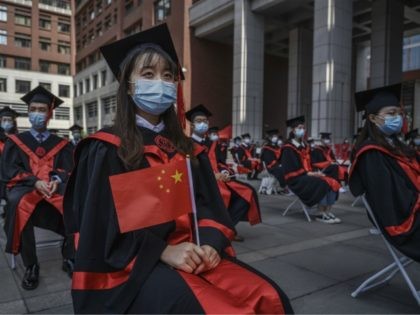 BEIJING, CHINA - JUNE 30: A Chinese student from Renmin University of China holds a flag as she sits with others as they are seated to adhere to social distancing during their graduation ceremony at the school's campus on June 30, 2020 in Beijing, China. Renmin University, also known as …