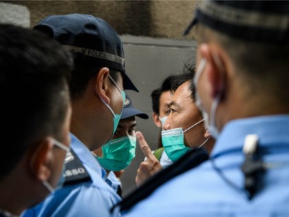 Police interrupt a march by a group of pro-democracy protesters (C), before issuing them with fines for breaking government-imposed social distancing rules against the COVID-19 coronavirus, during their route from outside the Western Police Station to the Chinese Liaison Office in Hong Kong on May 22, 2020. - A proposal …