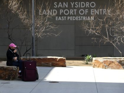 SAN DIEGO, CALIFORNIA - MARCH 21: A traveler sits down outside the U.S. Customs and Border Protection - San Ysidro Port of Entry on March 21, 2020 in San Diego, California. The United States and Mexico announced a temporary ban on non-essential and leisure travel across the U.S. - Mexican …