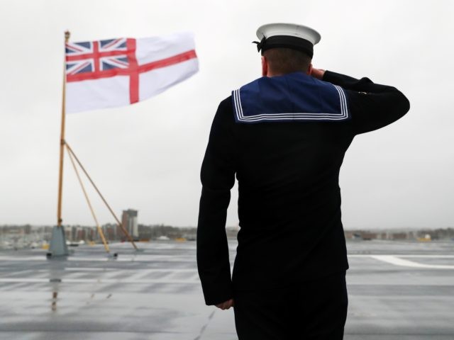 Members of the ship's company raise the White Ensign on the stern of the Royal Navy aircraft carrier, HMS Prince of Wales, during her commissioning ceremony at Portsmouth Naval Base, south England on December 10, 2019. (Photo by Andrew Matthews / POOL / AFP) (Photo by ANDREW MATTHEWS/POOL/AFP via Getty …